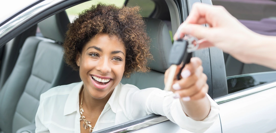 Happy young woman getting the keys for her new car.