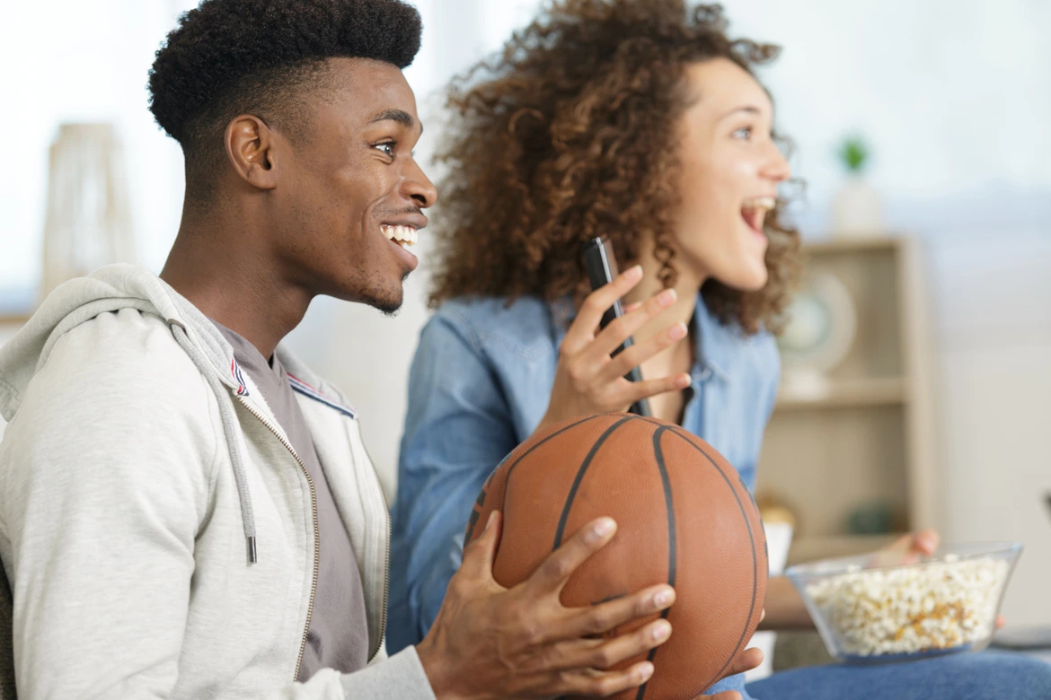 Excited couple watching basketball at home