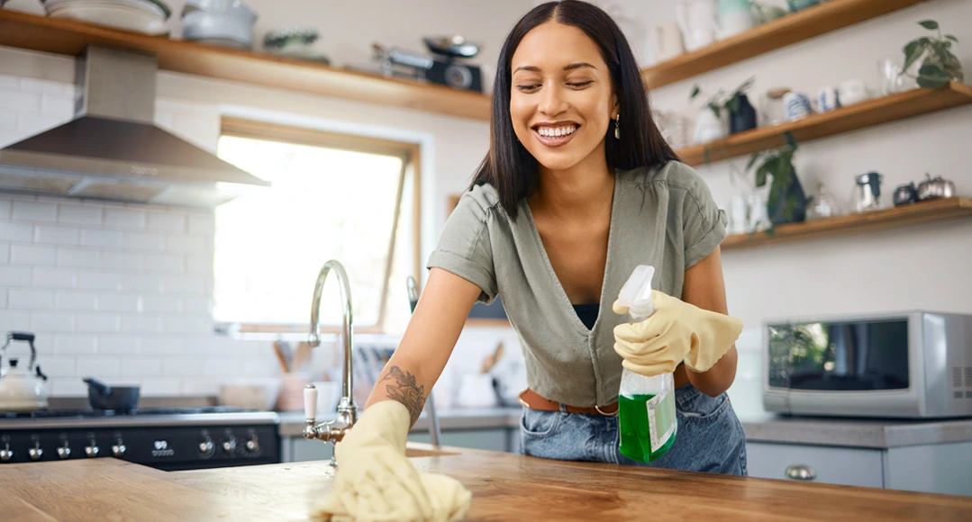 Smiling woman cleaning a kitchen counter